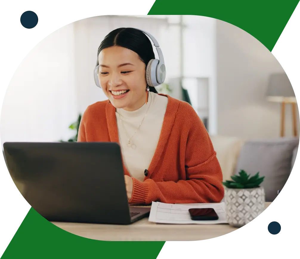 A woman in red cardigan wearing a headphone smiling at her laptop